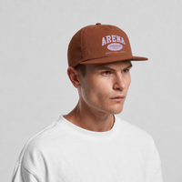 A man wearing a brown snapback cap with a white 'ARENA' logo, paired with a white t-shirt, photographed against a light gray studio background.