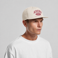 A man wearing a cream-colored surf cap with a rose 'ARENA' logo on the front, paired with a white crewneck t-shirt, against a light gray studio background.