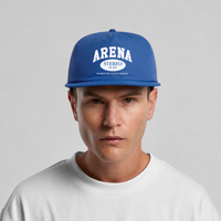 A man wearing a royal blue snapback cap with white 'ARENA STEREO' text on the front, paired with a white t-shirt against a light gray background.