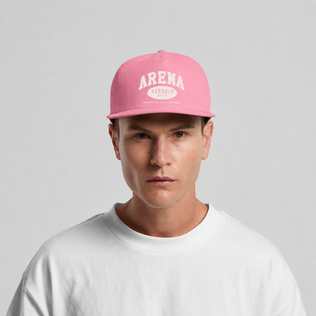 A man wearing a pink snapback cap with 'ARENA' printed in white on the front, paired with a white t-shirt, against a light gray background.
