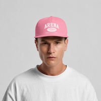 A man wearing a pink snapback cap with 'ARENA' printed in white on the front, paired with a white t-shirt, against a light gray background.