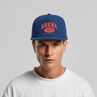 A man wearing a blue snapback cap with red and orange 'ARENA STEREO' text on the front, paired with a white t-shirt, against a light gray background.