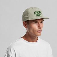 A man wearing a light sage green baseball cap with green 'ARENA' branding, paired with a white t-shirt, against a neutral gray background.