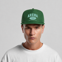 A man wearing a forest green flat-brim cap with 'ARENA STEREO' printed in cream on the front, paired with a white crewneck t-shirt, set against a plain light gray background.
