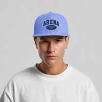 A man wearing a light blue snapback cap with 'ARENA STEREO' printed on the front, paired with a white t-shirt against a light gray background.
