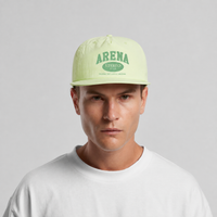 A man wearing a light lime green snapback cap with green 'ARENA STEREO' text on the front, paired with a white t-shirt, against a neutral gray background.