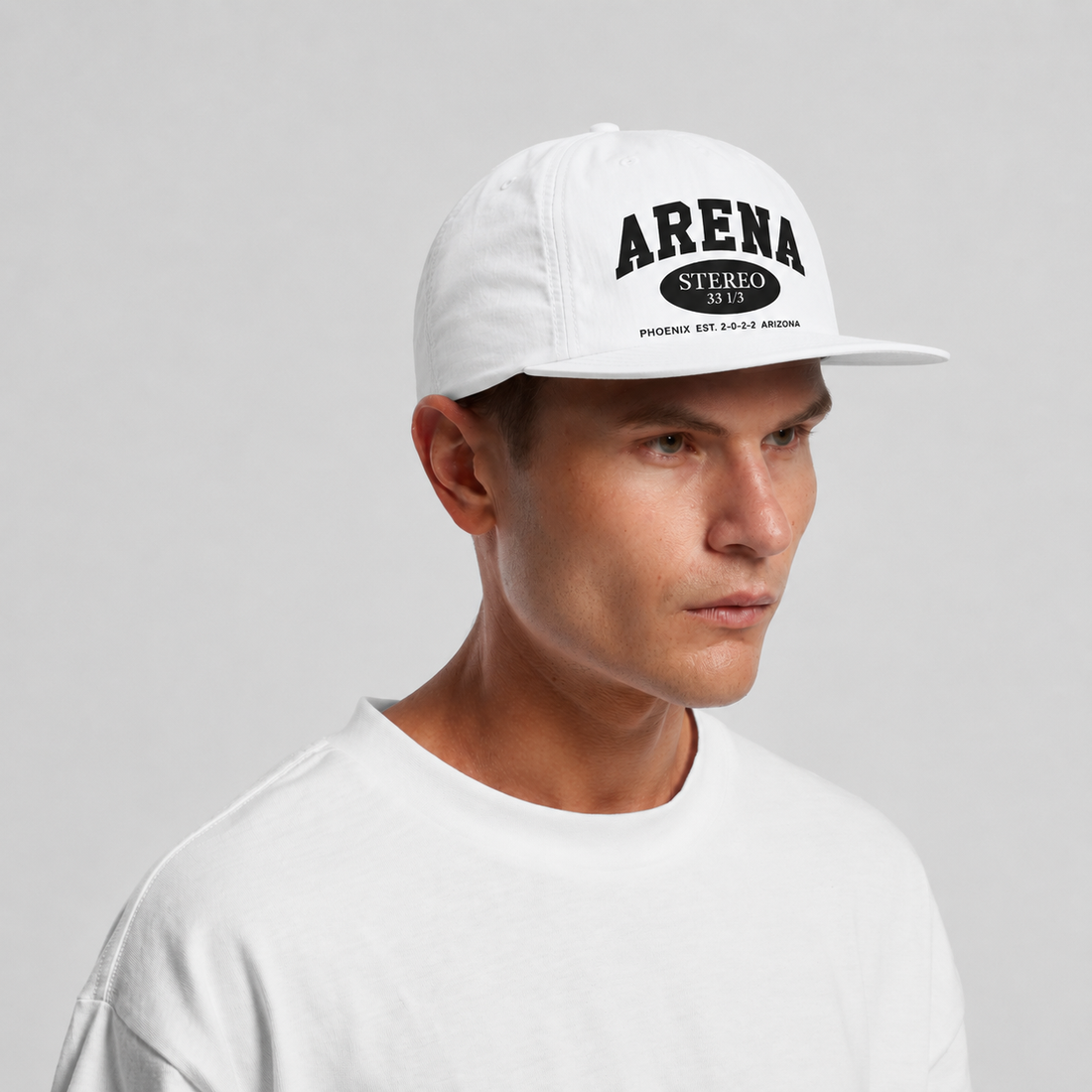 A man wearing a white snapback cap with black 'ARENA STEREO' text on the front, photographed against a light gray studio background.