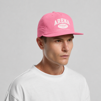 A man wearing a pink baseball cap with 'ARENA' printed in white on the front, paired with a white t-shirt, against a light gray studio background.
