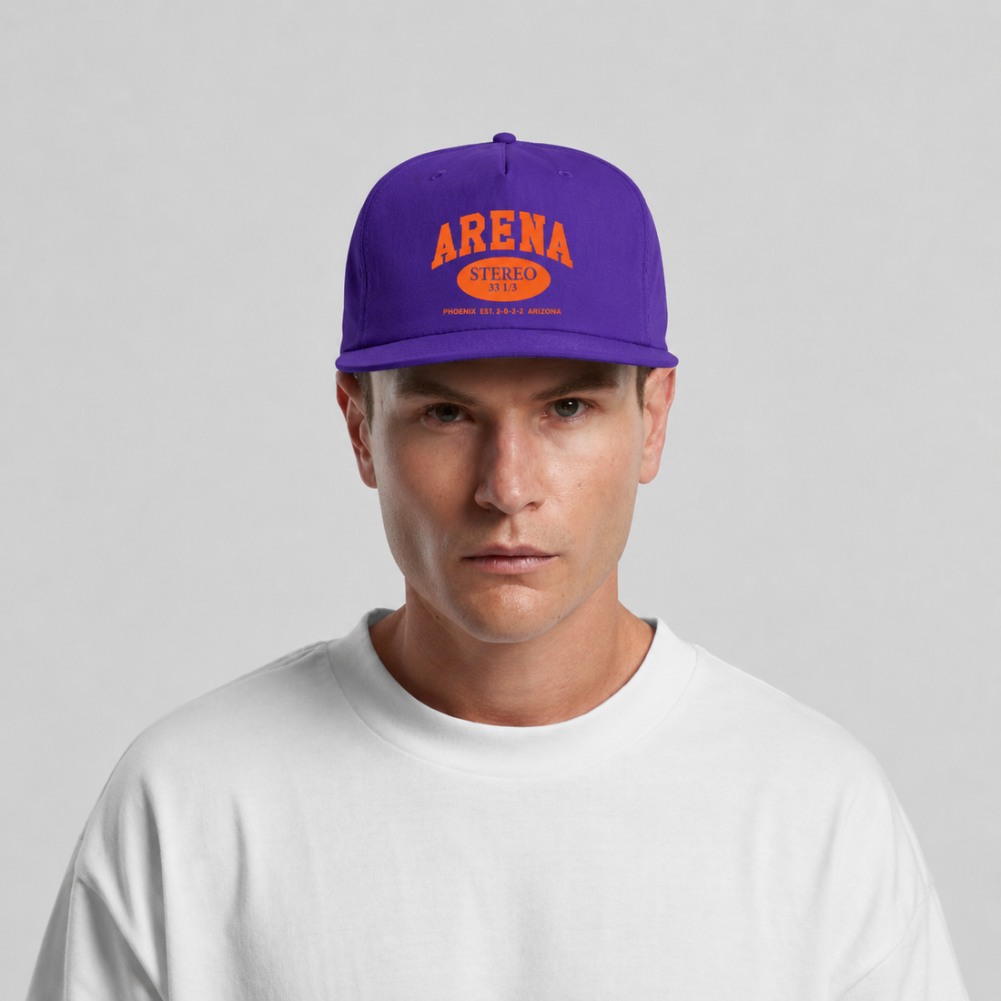A man wearing a purple snapback cap with orange 'ARENA' and 'STEREO 33 1/3' text on the front, paired with a white t-shirt against a light gray background.