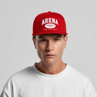 A man wearing a bright red snapback cap with 'ARENA STEREO' printed in white on the front, paired with a white crewneck t-shirt, against a light gray studio background.