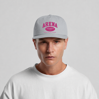 A man wearing a light gray snapback cap with a pink 'ARENA STEREO' graphic on the front, paired with a white t-shirt, against a light gray background.