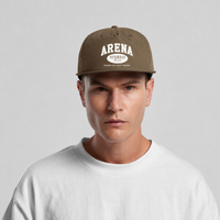 A man wearing a brown snapback cap with 'ARENA STEREO' printed in white on the front, paired with a white t-shirt, against a light gray background.