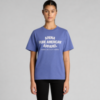 A model wearing a lapis blue crewneck t-shirt with white text reading 'ARENA PURE AMERICAN APPAREL' on the chest, paired with black pants, against a solid gray studio background.